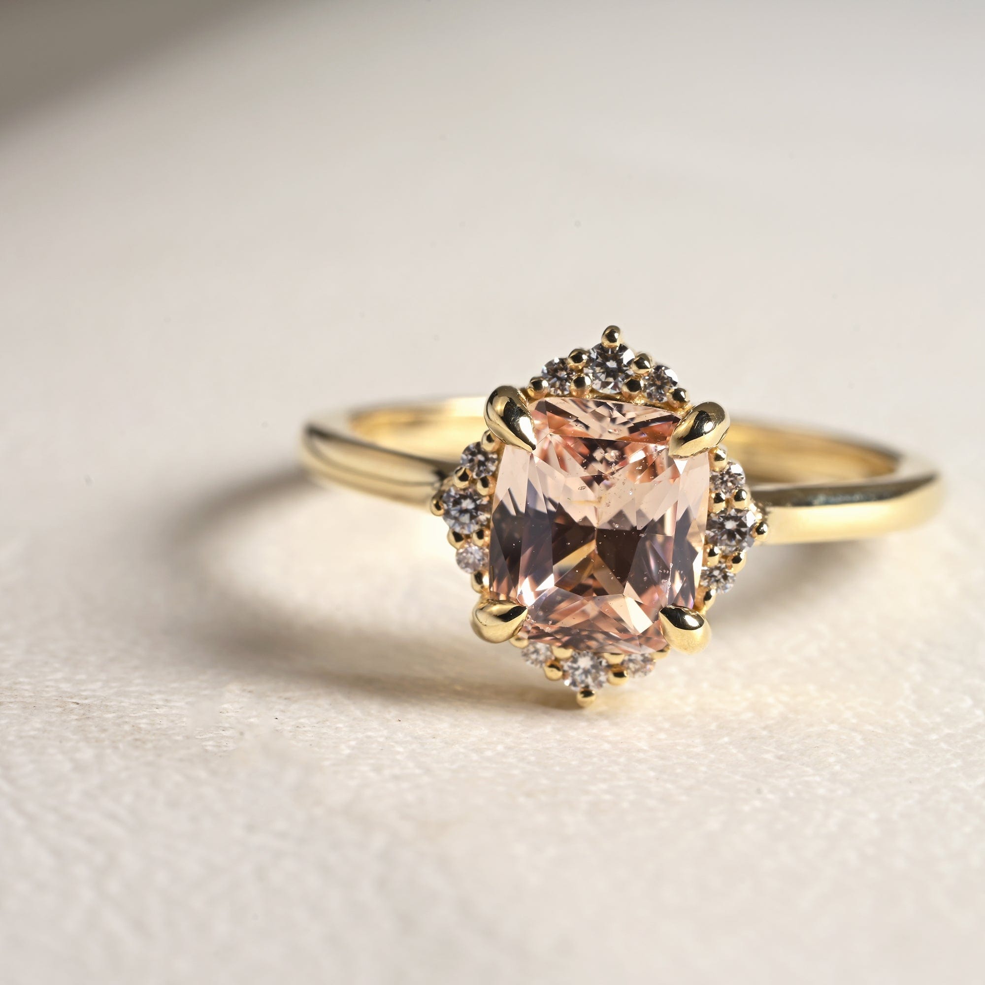 14k yellow gold halo engagement ring with peach cushion cut sapphire