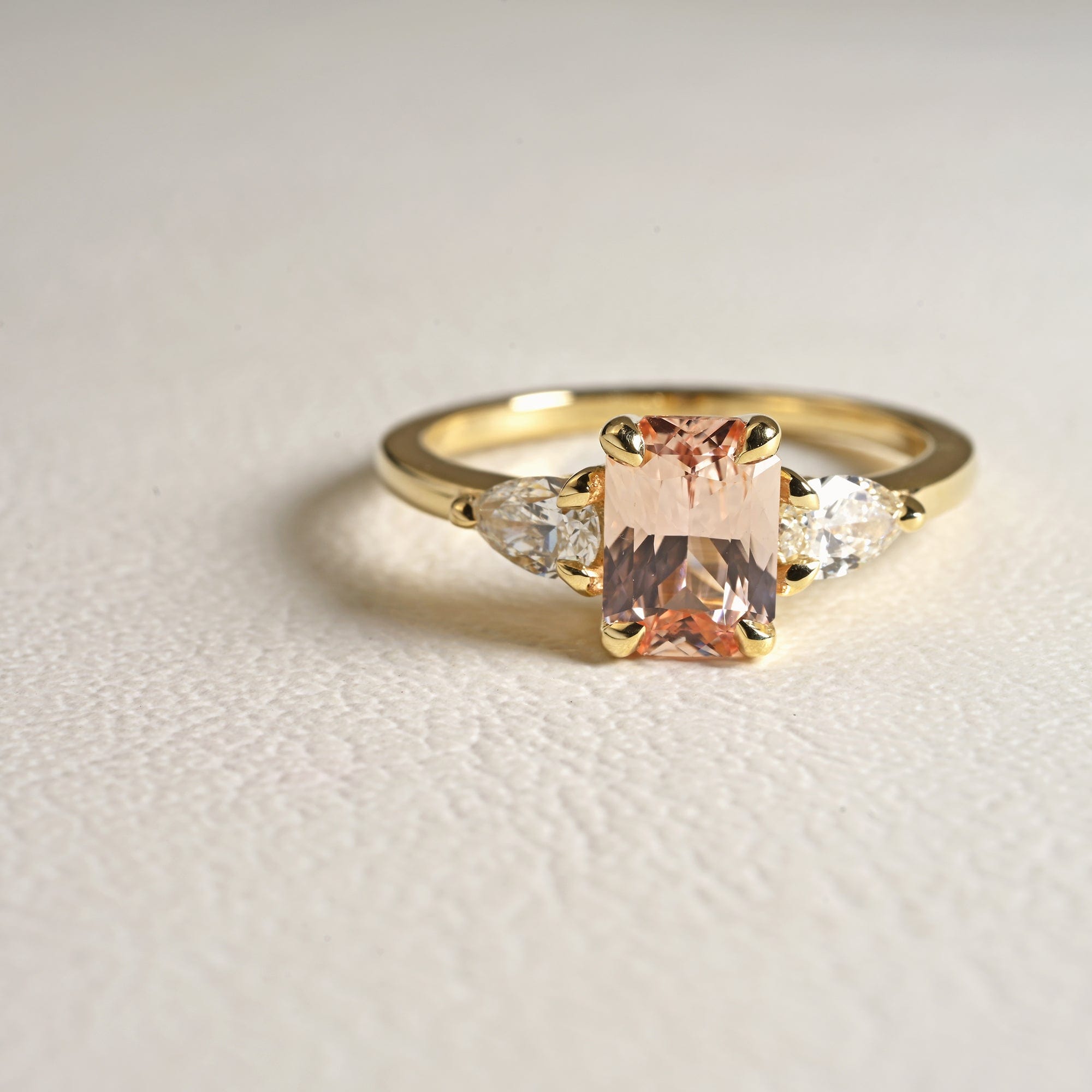 14k yellow gold three stone engagement ring, peach radiant cut sapphire with pear diamond sides