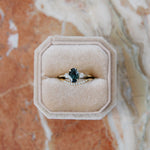 Curved diamond wedding ring and 14k yellow gold engagement ring with teal green oval sapphire and diamonds