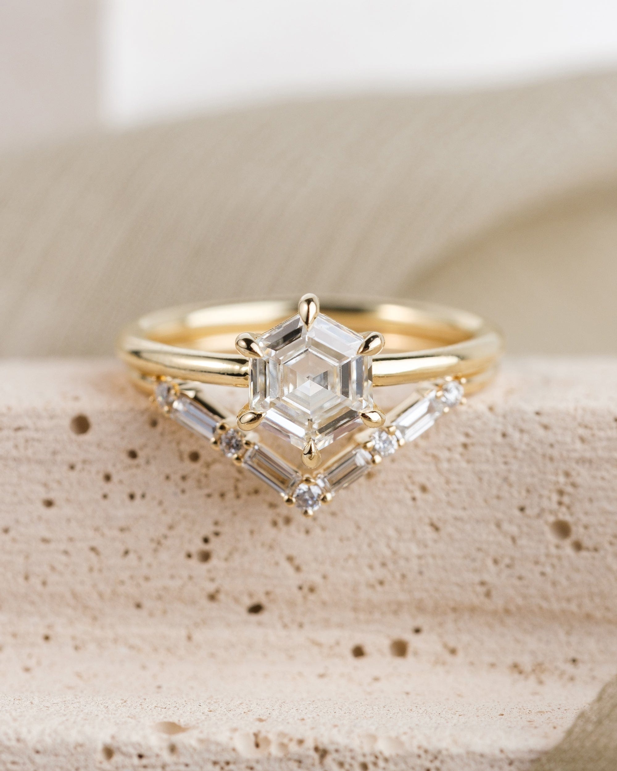 Hexagon diamond engagement ring 14k yellow gold solitaire setting with six prongs, paired with a v shaped wedding band that features 4 baguette and 5 round diamonds