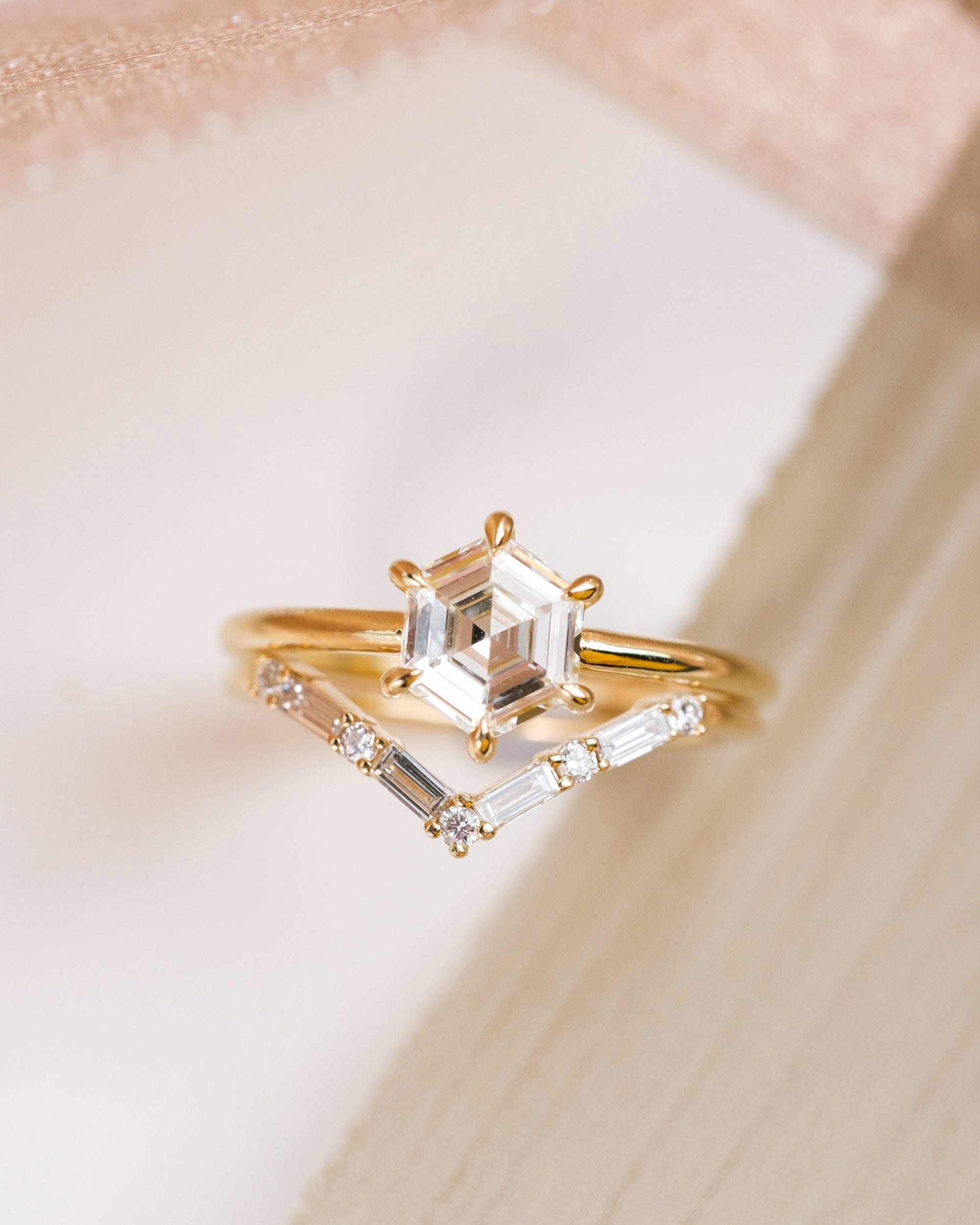 Modern hexagon diamond engagement ring 14k yellow gold solitaire setting with six prongs, paired with a v shaped wedding band that features 4 baguette and 5 round diamonds