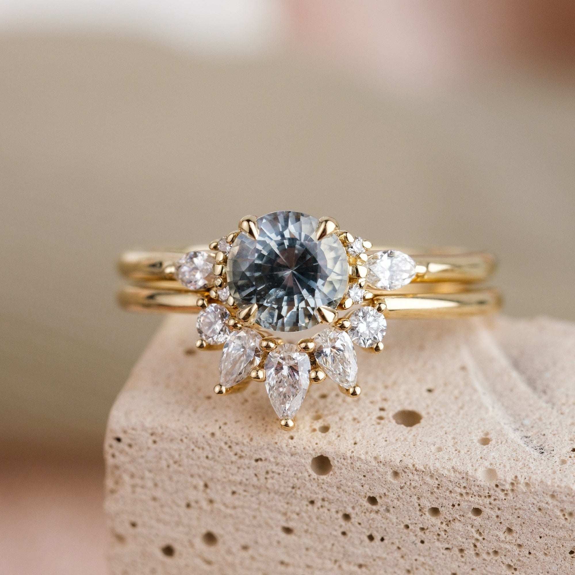 A stormy gray-blue sapphire engagement ring with 6 accent diamonds set in 14k yellow gold, paired with a 5 diamond wedding band in 14k yellow gold