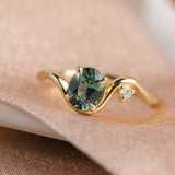 Sculptural 14k yellow engagement ring featuring oval teal sapphire and white accent diamond