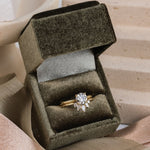 14k yellow gold solitaire diamond ring paired with a 14k yellow gold wedding band with 5 diamonds, sitting in an olive green velvet box