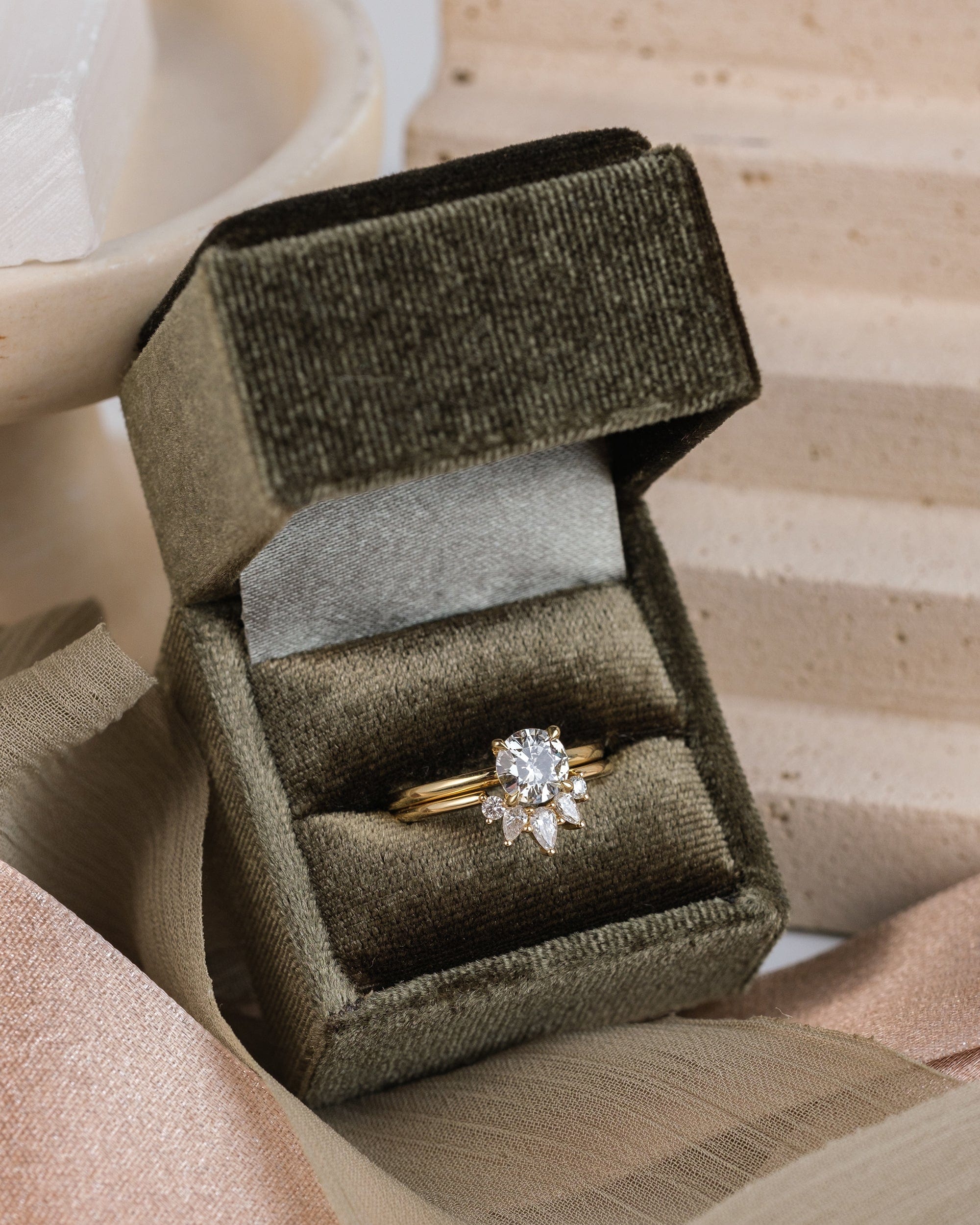 14k yellow gold solitaire diamond ring paired with a 14k yellow gold wedding band with 5 diamonds, sitting in an olive green velvet box