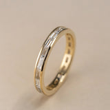 Vertical view of a channel set baguette diamond wedding band in 14k yellow gold